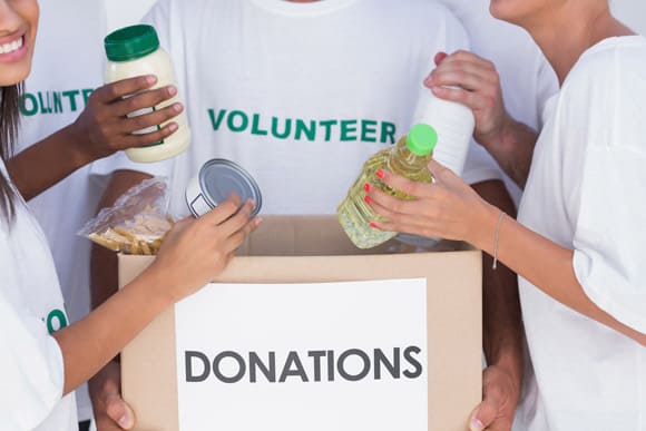 Group of volunteers putting food in donation box Giving Tuesday