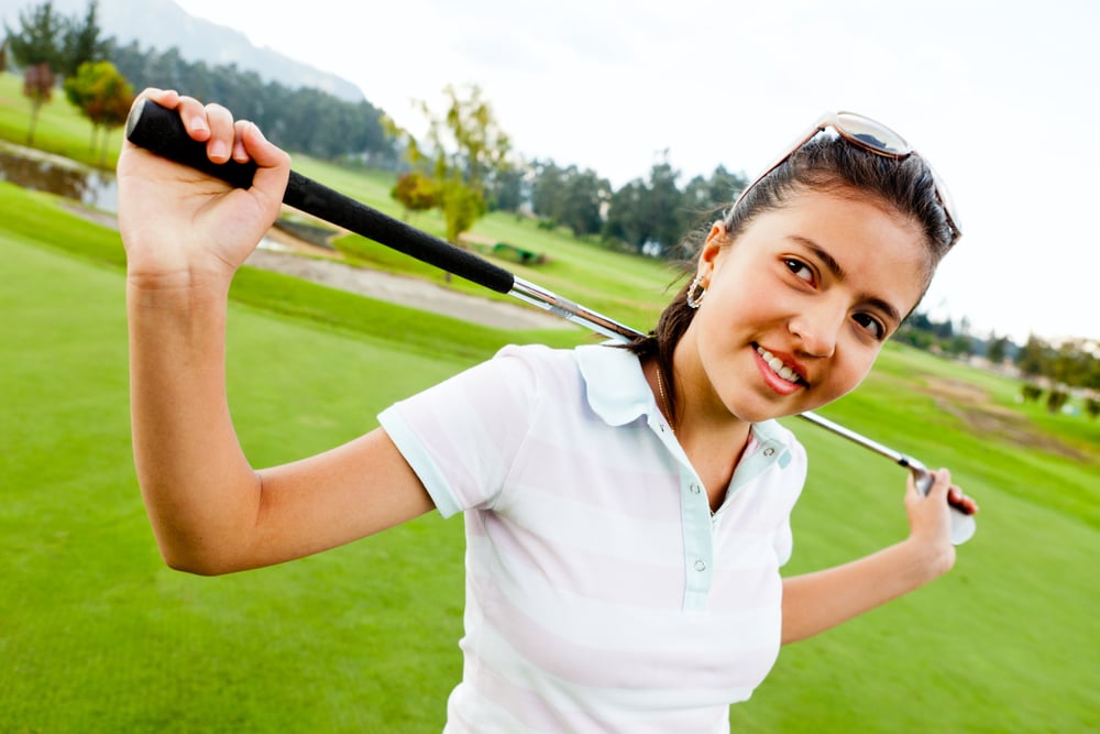 woman holding club behind her neck on a golf course